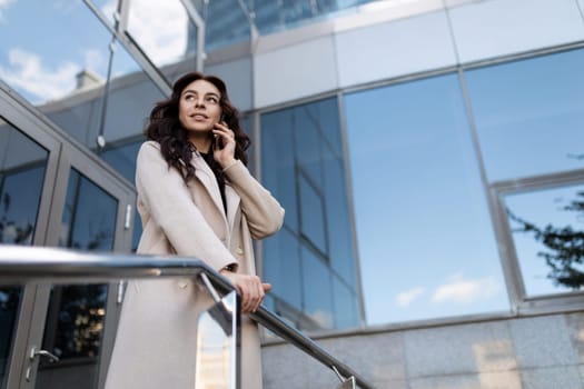 Business woman talking on a mobile phone at the entrance to an office building.