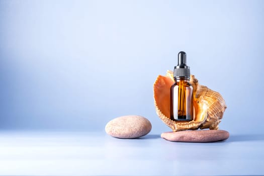 Glass brown bottle with a pipette for a cosmetic product with a sea shell on stones. Natural cosmetics for face and body skin care. Selective focus. Place for text.