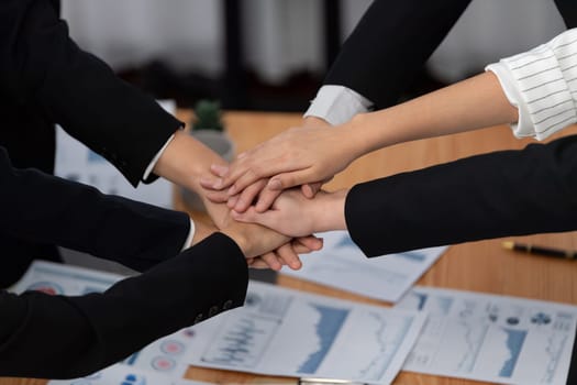 Top view closeup business team of suit-clad businesspeople join hand stack together. Colleague collaborate and work together to promote harmony and teamwork concept in office workplace.