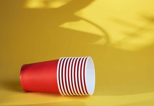 red paper coffee cups on a yellow background are the morning concept of disposable tableware