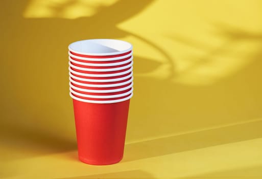 red paper coffee cups on a yellow background are the morning concept of disposable tableware