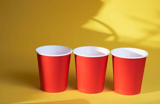 three red paper coffee cups on a yellow background is a morning concept