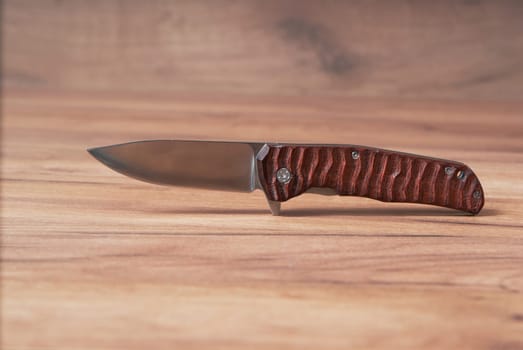 hunting knife on a wooden background with a beautiful pattern on a wooden handle