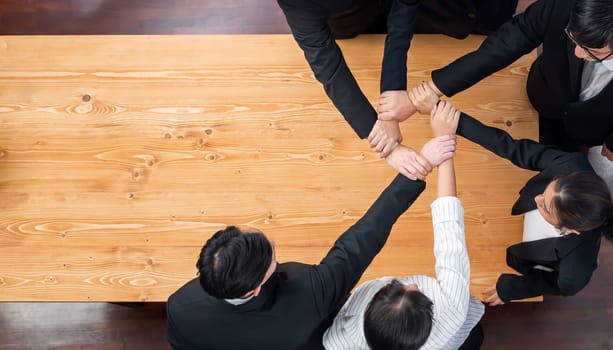 Top view cohesive group of business people join hands stack together, form circle over meeting table for copyspace. Colleagues working to promote harmony and synergy team building concept in workplace
