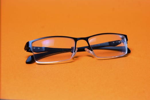 The glasses are on a bright orange background close-up
