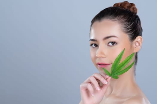 Closeup glamorous beautiful woman with soft make up and flawless smooth clean skin holding green leaf. Cannabis skincare cosmetic product for natural skin treatment concept in isolated background