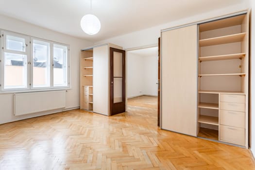 an empty room in an apartment with a wardrobe and a wooden parquet floor. High quality photo