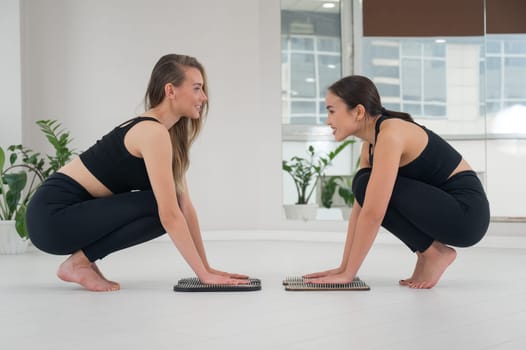 Caucasian and Asian women keep their hands on sadhu boards. Nailing practice