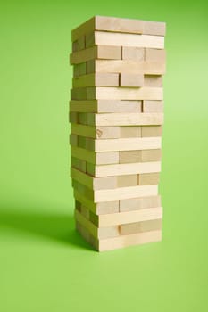 Wooden blogs stacked on isolated green background. Entertainment activities. Board game game of physical and mental skill, developing fine motor skills.