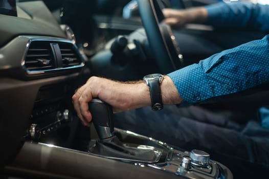 Close-up of a man's hand while shifting the automatic transmission of a car