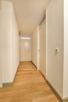 a long hallway with white walls and wood flooring on either side of the room, there is an open door leading to another