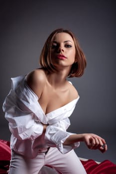 Sensual red-haired model posing at camera, on gray background