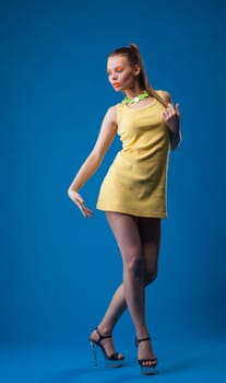 Graceful girl posing with disco makeup in studio, on blue background