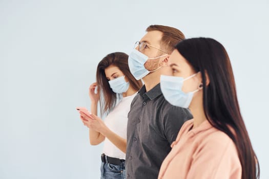 Three people standing together in the studio against white background.