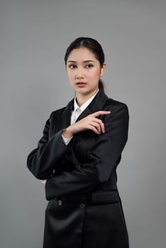 Confident young businesswoman stands on isolated background, posing in formal black suit. Office lady or manager with smart and professional appearance. Enthusiastic