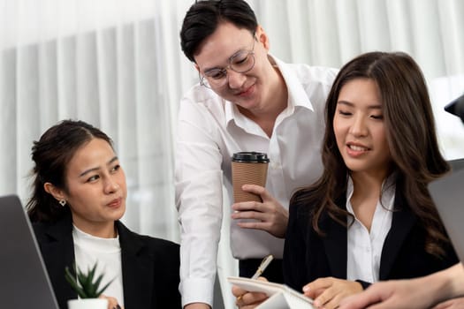 Harmony in office concept as business people analyzing dashboard paper together in workplace. Young colleagues give ideas at manager desk for discussion or strategy planning about project.