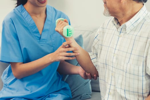 Contented senior patient doing physical therapy with the help of his caregiver. Senior physical therapy, physiotherapy treatment, nursing home for the elderly