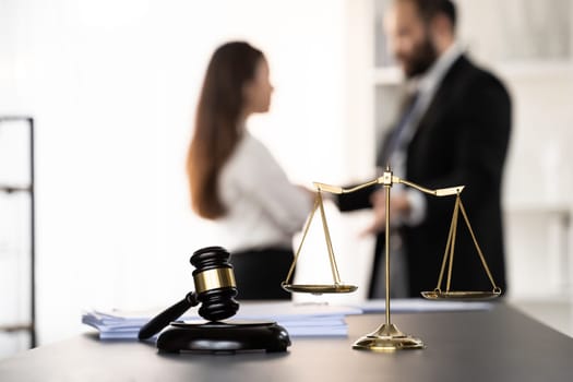 Balanced scale of justice and gavel hammer in focus on blurred background of lawyer colleagues discuss and plan for lawsuit in law firm office, as legal representatives. Equilibrium