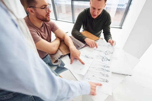 Cloth and fashion business. Three people works in the office by sitting by the table.