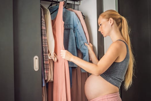 A pregnant woman has nothing to wear. A pregnant woman stands in front of a closet with clothes and does not know what to wear because the clothes do not fit on her.