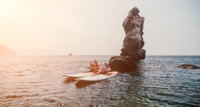 Woman sup yoga. Middle age sporty woman practising yoga pilates on paddle sup surfboard. Female stretching doing workout on sea water. Modern individual hipster outdoor summer sport activity