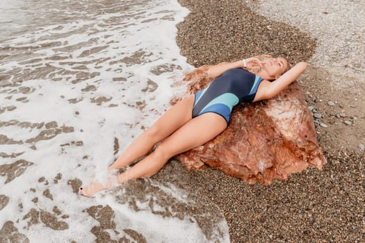 Woman travel sea. Young Happy woman in a long red dress posing on a beach near the sea on background of volcanic rocks, like in Iceland, sharing travel adventure journey