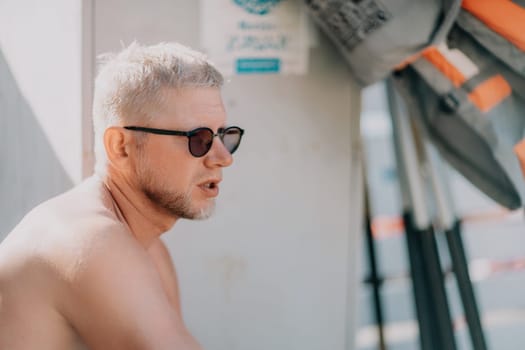 Outdoor portrait of young smiling Caucasian man in white sunglasses on summer ocean coast