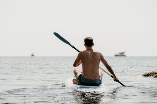 Side view foto of a man swiming and relaxing on the sup board. Sportive man in the sea on the Stand Up Paddle Board SUP. The concept of an active and healthy life in harmony with nature