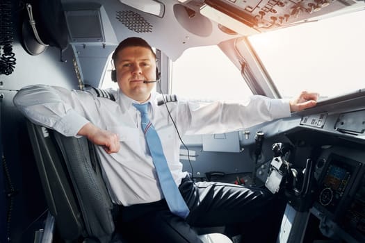 Pilot in formal wear sits in the cockpit and controls airplane.