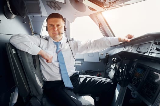 Pilot in formal wear sits in the cockpit and controls airplane.