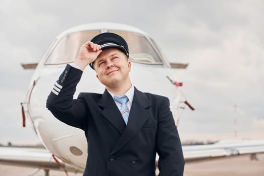 Experienced pilot in uniform standing outside near plane.