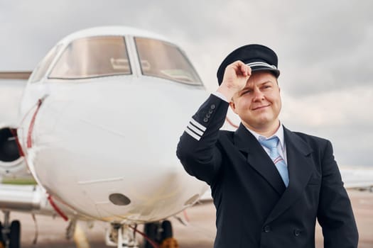 Experienced pilot in uniform standing outside near plane.