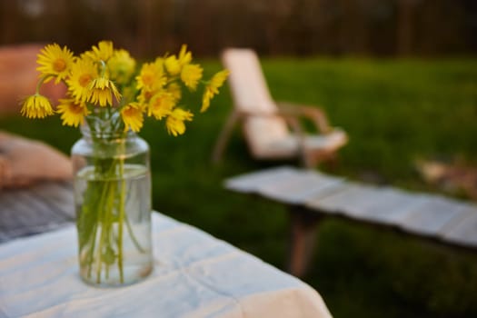 yellow wild flowers stand in a transparent vase on the street. High quality photo