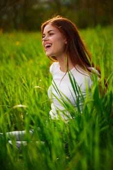 portrait of a laughing red-haired woman sitting in the grass. High quality photo