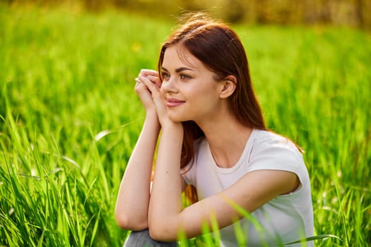 Portrait of young beautiful pensive dreamy woman lying on grass at summer green park . High quality photo