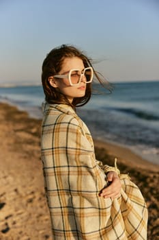 portrait of a beautiful woman with red hair blown by the wind on the sea coast wrapped in a plaid. High quality photo