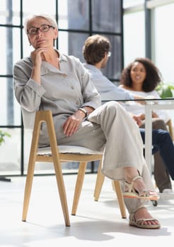 mature woman sitting with laptop looking at camera.