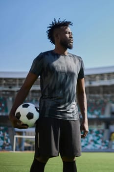 A young man stands in a stadium with a soccer ball in his hand