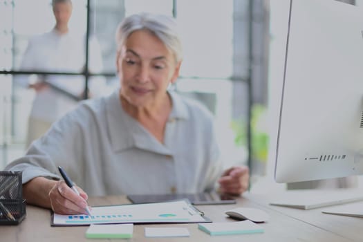 The older stylish woman takes notes in a document .