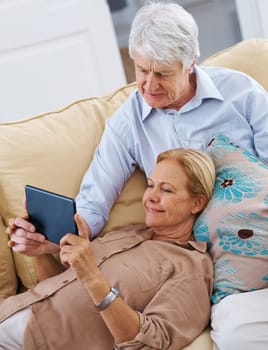 The little romance creator. a senior woman lying on her husbands lap while using her digital tablet