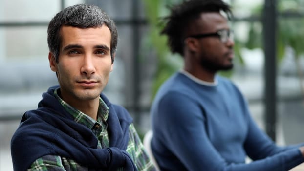 Close-up portrait of a handsome successful businessman in the office against the background of his African-American colleague