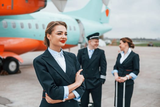 Aircraft crew in work uniform is together outdoors near plane.
