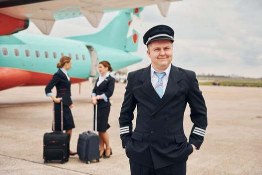 Aircraft crew in work uniform is together outdoors near plane.