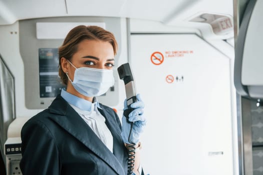 Uses phone. Young stewardess on the work in the passanger airplane.