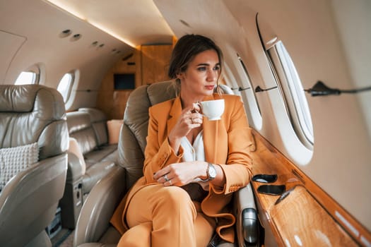 Young passenger woman in yellow clothes is flying in the plane.