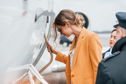 A young woman in yellow clothes is accompanied by an airline workers.