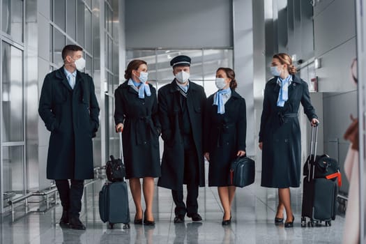 Aircraft crew in work uniform is together outdoors in the airport.