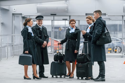 Aircraft crew in work uniform is together outdoors in the airport.