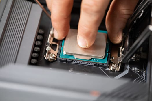 A close-up of the fingers holding the processor. Gently and carefully connecting a new computer part. Purchasing and replacing computer parts to increase the performance of the device.