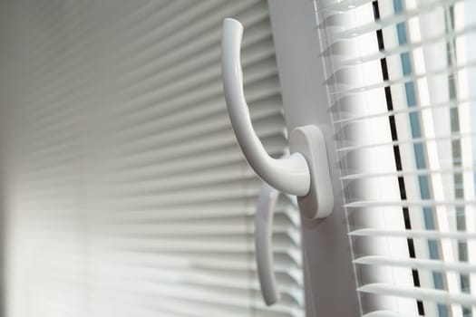 Open plastic window for ventilation. Handle up and down. PVC metal blinds on the window frame.